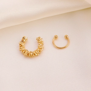 Detail von goldenen strukturierten Earcuffs auf weichem Satin-Hintergrundstoff
