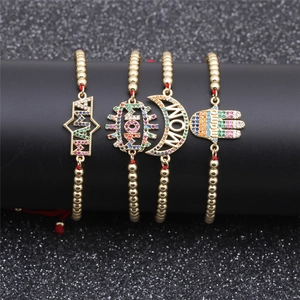 Detail of four gold beaded bracelets with colorful zircon MAMA pendants on black stand