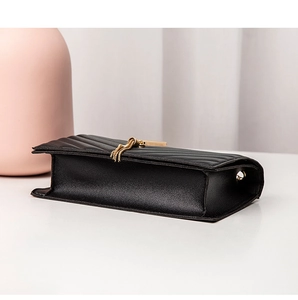 Detail view of the black quilted small square bag with elegant gold metal tassel accents