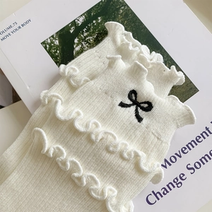 Close-up of white ruffled ankle socks with exquisite black bow embroidery details