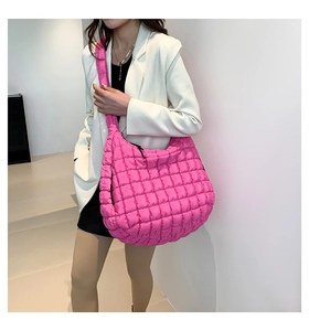 Macro detail of bright pink quilted puffer bag showing glossy grid texture and large capacity
