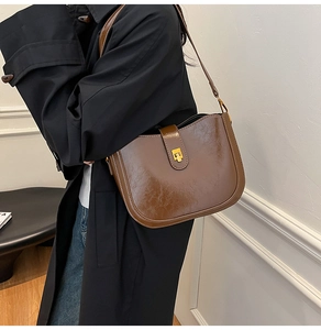 Detail of vintage brown saddle bag with glossy oil wax leather and gold metal buckle