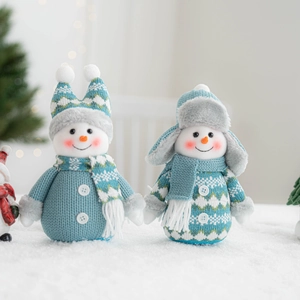 Charming knitted Christmas snowman dolls in blue and white on snow for festive decoration