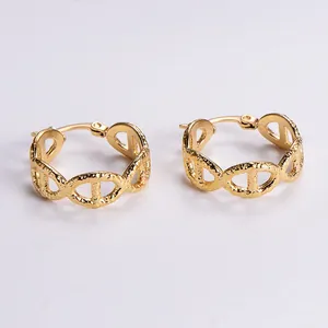 Macro view of gold hoop earrings with anchor chain design and hammered matte texture
