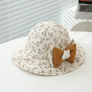 Detailed close-up of a floral baby sun hat with a brown bow and cute plush bunny ornament