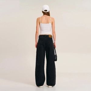 Full back view of a woman wearing white cross-print camisole and black wide-leg jeans