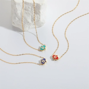 Golden Hamsa Hand necklaces with blue and red enamel eyes on a clean white background
