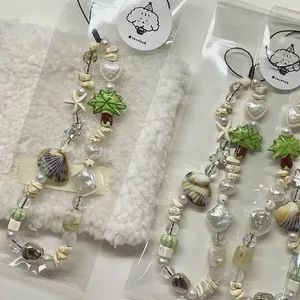 Beaded summer phone charm with seashell starfish and palm tree charms on white background