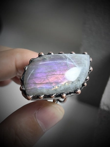 Macro shot of natural labradorite gemstone with purple flashes in vintage bronze ring