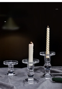 Three transparent glass pillar candle holders in varying heights with ribbed candles