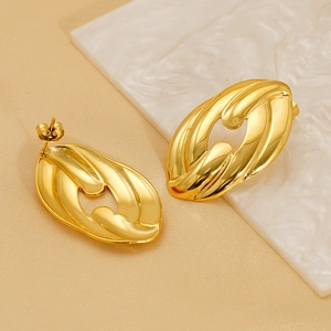 Detailed view of gold woven metal stud earrings on a textured marble background