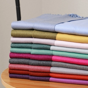 Close-up of neatly stacked colorful double-sided cashmere scarves with soft fringe edges