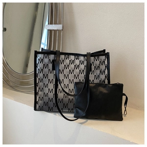 Detail view of transparent M-pattern tote bag with internal black zipper pouch insert