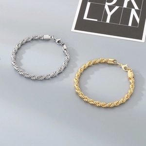Détail de bracelets chaîne torsadée en or et argent avec fermoir mousqueton robuste