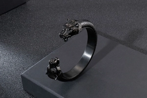 Detail of matte black wolf head open cuff bracelet on dark geometric display stand