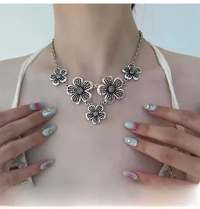 Detail view of retro silver hollow flower necklace featuring aged floral pendants