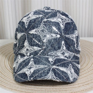Detailed close-up of blue denim baseball cap featuring white star patterns and sequins