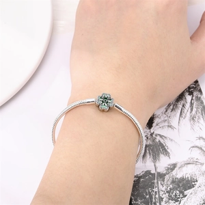 Close-up of silver clover bracelet with green crystal and diamonds on model wrist
