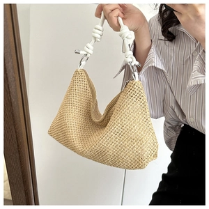 Detail of hand-woven straw tote bag with white knotted handles and natural texture