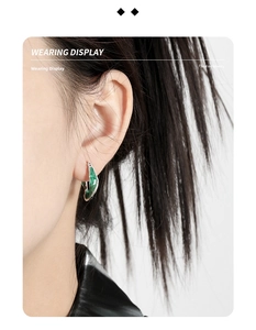 Detail of twisted silver earrings with green enamel on ear, modern art style