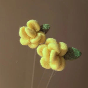 Macro detail of yellow velvet flower earrings with green leaf accent and soft texture