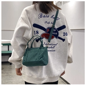 Green corduroy Boston mini bag worn as a crossbody bag in a stylish lifestyle setting