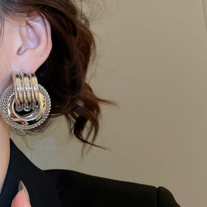 Gros plan de boucles d'oreilles créoles torsadées en métal argenté sur un mannequin