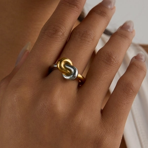 Two-tone interlocking knot ring in gold and silver finish on model's finger