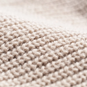 Close-up of beige knit beanie featuring thick wool texture and trendy turnover cuff