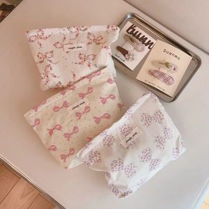 Close-up of pink bow and floral fabric cosmetic bags with hair accessories on a tray