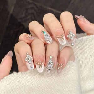 Close-up of pink cat-eye press-on nails with 3D rhinestones and Christmas tree decor