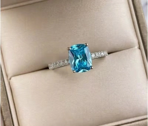 Detail of square blue zircon ring with small side diamonds in a beige jewelry box