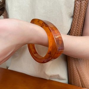 Gros plan d'un large bracelet en résine ambrée avec texture écaille de tortue polie
