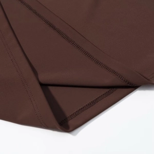 Vue macro du tissu marron foncé montrant les coutures plates et les détails de surjet