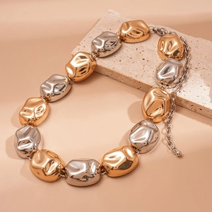 Close-up of gold and silver irregular metallic beads with wrinkled texture on stone