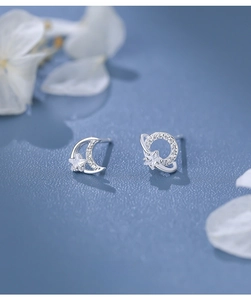 Macro detail of asymmetric S925 sterling silver moon and star earrings with cubic zirconia