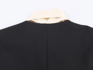 Detailed view of the contrast color collar stitching on the black blazer jacket
