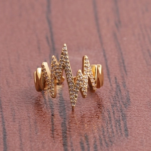 Golden pulse wave open ring with cubic zirconia stones on dark wood background