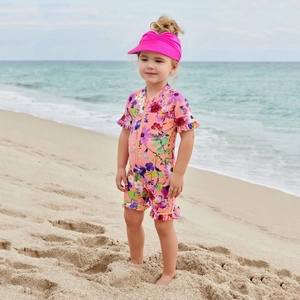 Detailed view of floral long sleeve toddler swimsuit with a matching bright pink sun hat