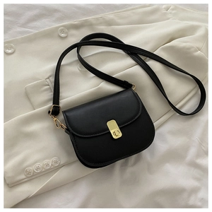 Detail of black leather saddle bag featuring a polished gold rotating clasp on a blazer