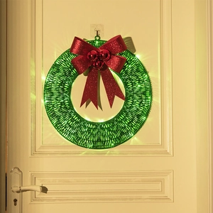 Christmas wreath with large red bow and LED warm lights hanging on a white wooden door