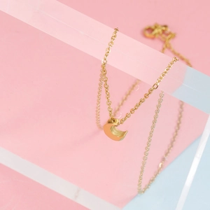 Collier avec pendentif croissant de lune doré poli suspendu sur un support épuré