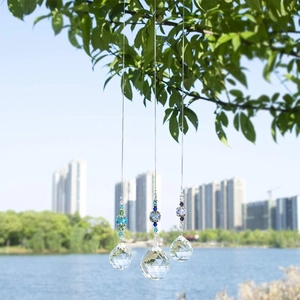 Detailed view of crystal suncatchers with faceted prism balls hanging in a bright park