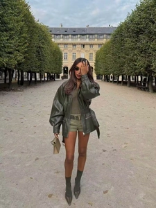 Detailed full-body street style of a green leather aviator jacket with matching belt and shorts