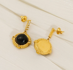 Détail de boucles d'oreilles dorées vintage avec pierre noire et éclats de zircon