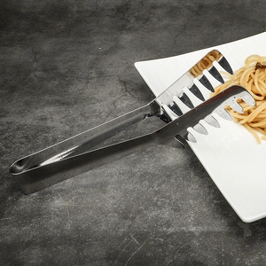 Macro shot of stainless steel pasta tongs with teeth picking up spaghetti on dark table