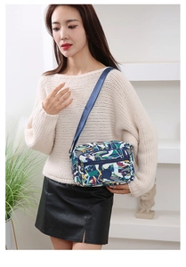 Close-up of functional nylon crossbody bag featuring multi-layer zippers and geometric print