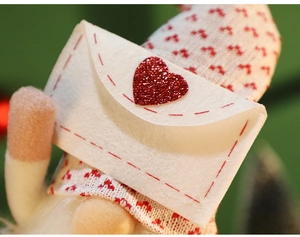 Close-up of cream felt envelope with red glitter heart and knit Christmas hat texture