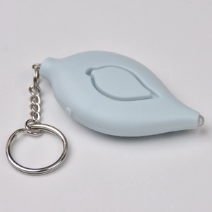 Macro view of light blue leaf-shaped personal alarm keychain with metal ring and chain