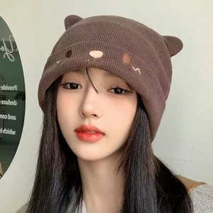 Brown knit beanie with cute bear ears and facial embroidery on a female model